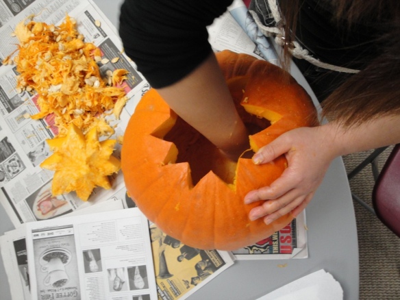 This is a picture of someone scooping the guts out of a pumpkin with their hand.