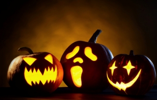 This is a photo of three carved and lit up pumpkins with spooky faces.