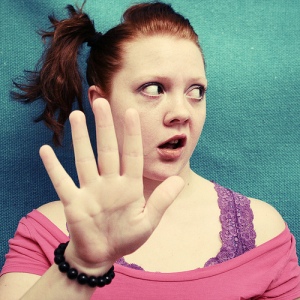 This is a photo of a valley girl with a side ponytail making the "talk to the hand" gesture.