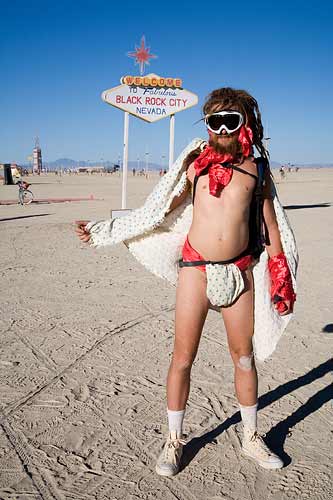 this is an image of a male festival-goer at Burning Man wearing basically a diaper, a cape and ski goggles.