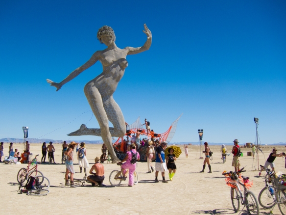 This is a photo of an art installation at Burning Man. It is an enormous sculpture of a nude woman in a dance-like pose.