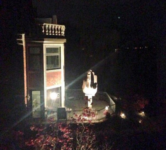 This is a photo of the middle finger statue at night with a spotlight trained on it